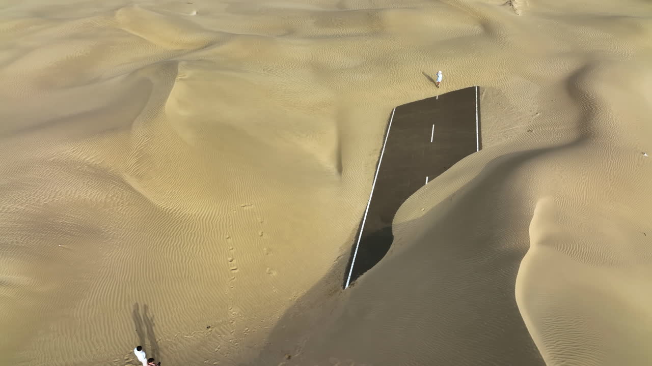 drone filmado alrededor de una persona caminando en la mitad de la carretera del desierto en el soleado dubái, eau