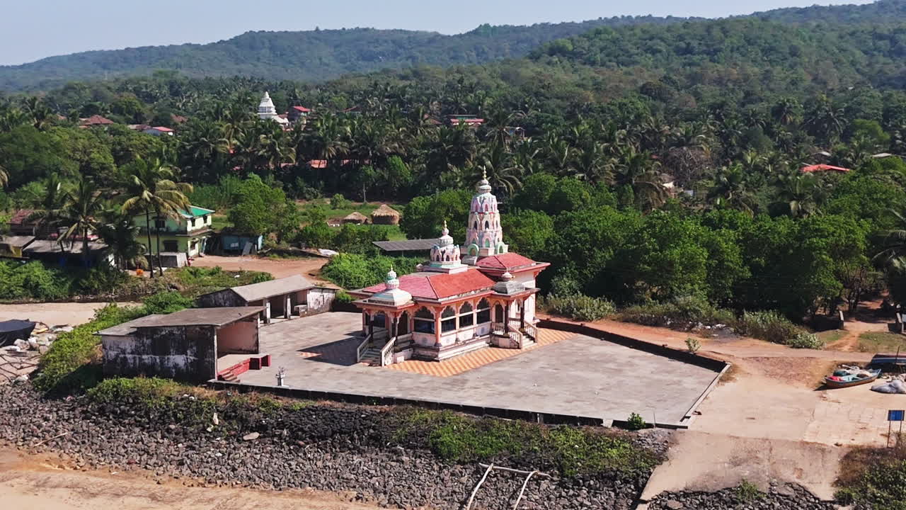 Drone flying around the Hanuman Mandir Hindu temple, sunny day in Guhagar, India