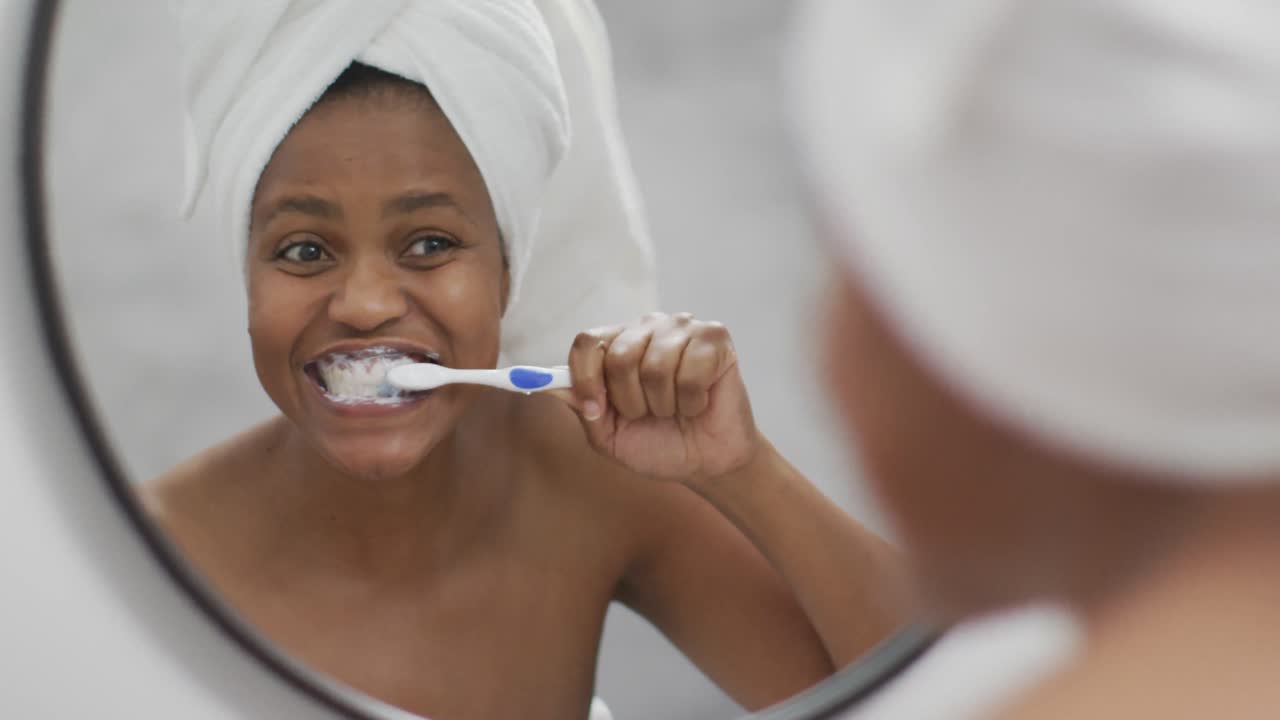 feliz mujer afroamericana cepillándose los dientes en el baño