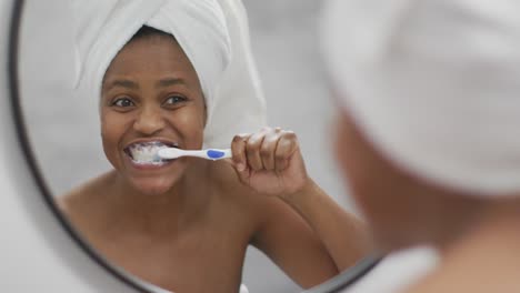 happy african american woman brushing teeth in bathroom