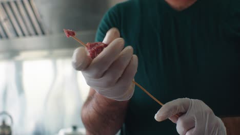 der koch drückt das fleisch auf den spieß