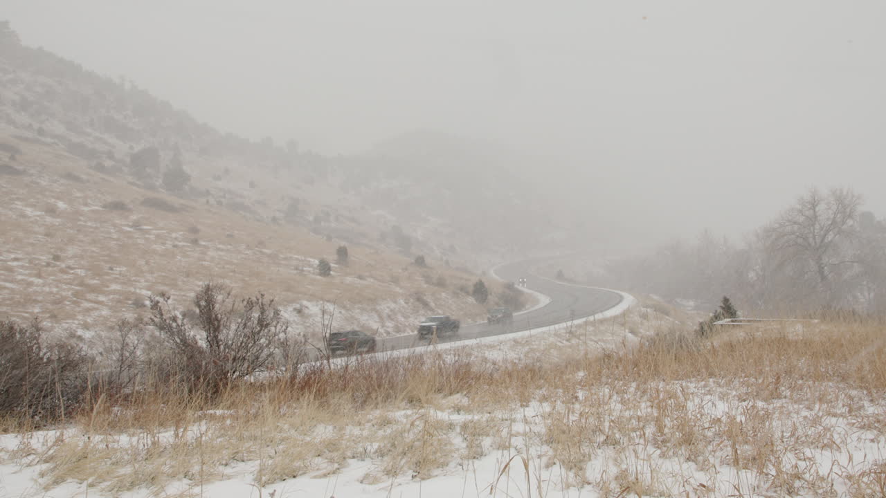 Cars drive on snowy road in a blizzard