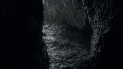 Cinematic-shot-through-dripping-cave-seeking-for-light