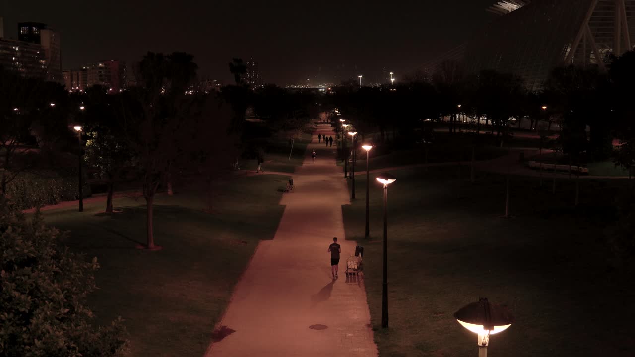 Nighttime park scene with people walking and running