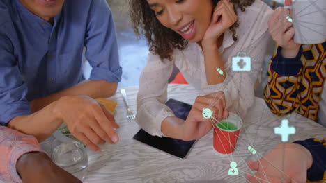 animation of network of connections with icons over diverse colleagues using laptop