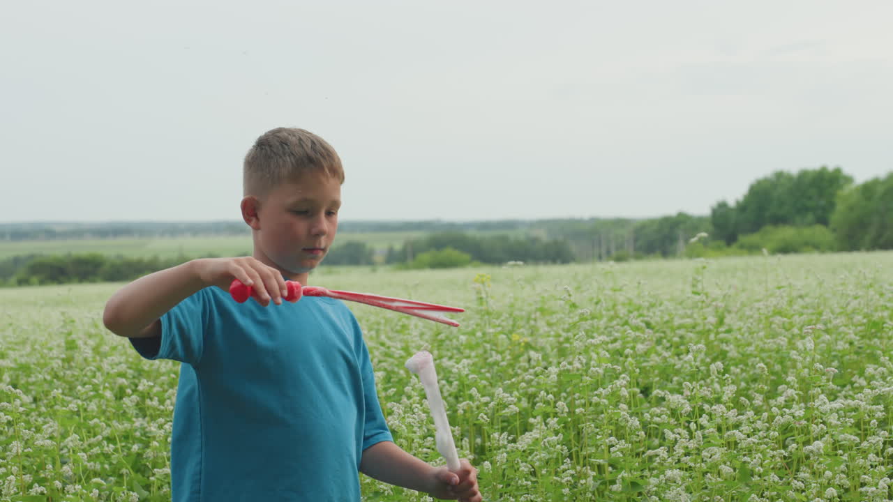 Young boy crafts star bubble in flower field, Child blows starshaped soap film amid blooming wildflowers, Young boy in wildflower field produces starshaped bubbles with joyful expression