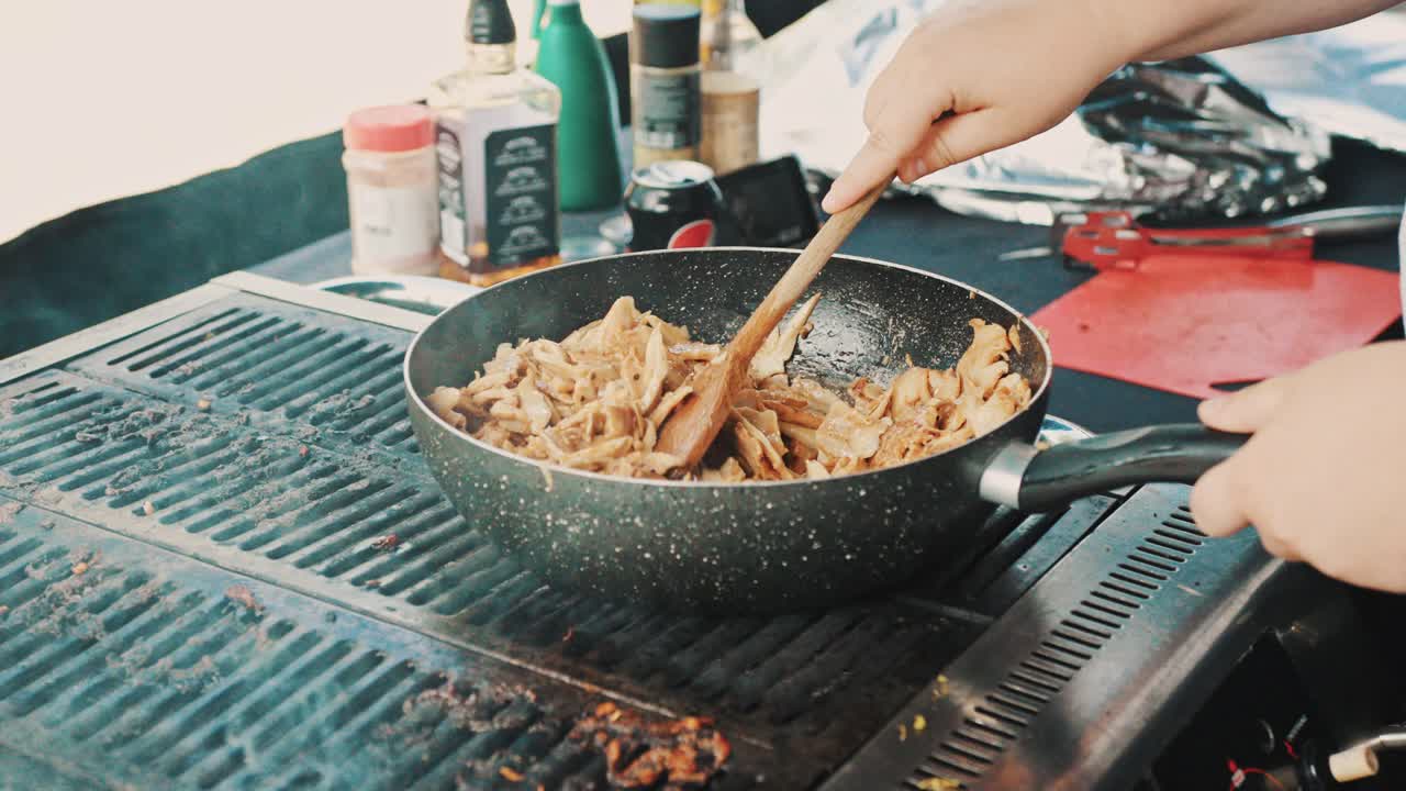 한 남자가 느린 움직임으로 bbq에 케 ⁇ 을  ⁇ 고 나무  ⁇ 가락을  ⁇ 는다.