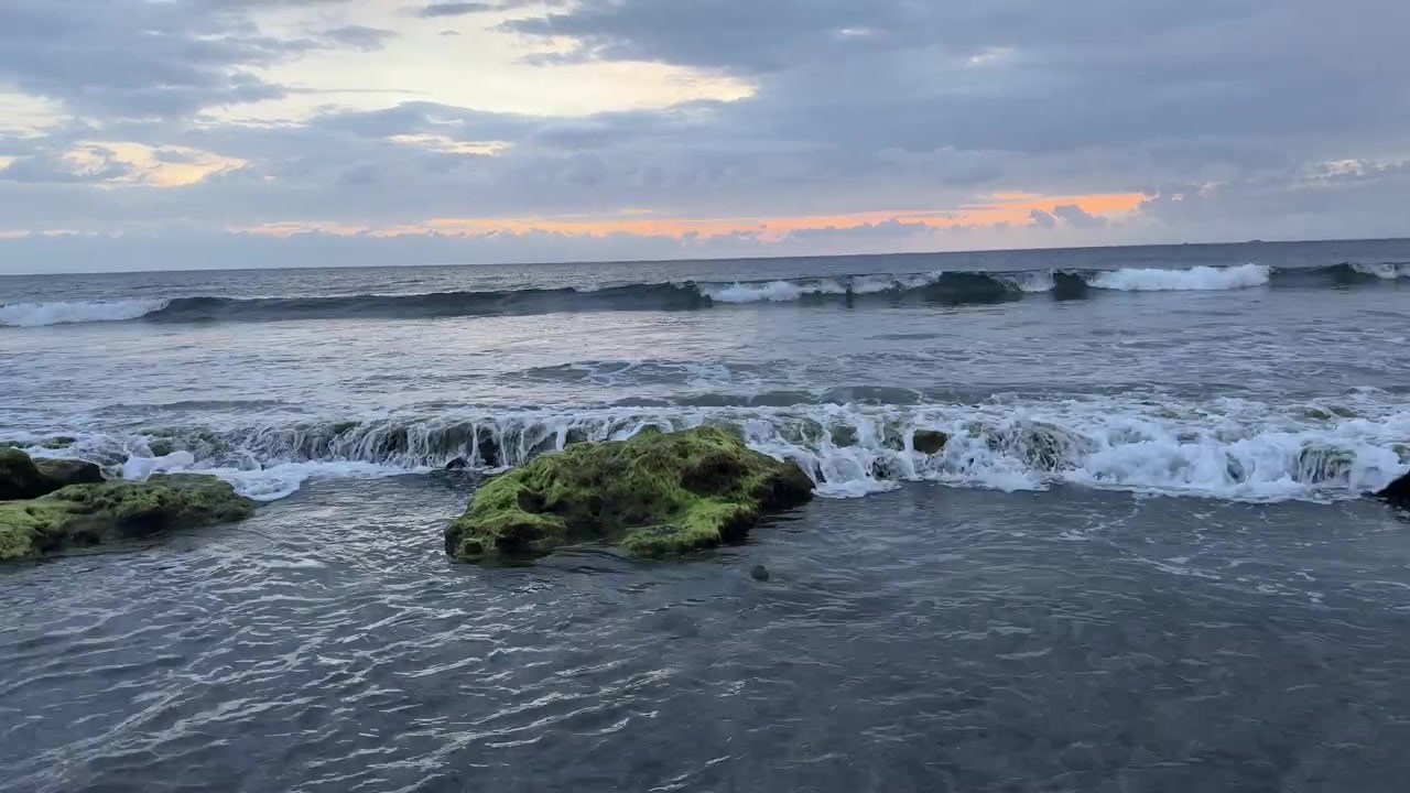 Onde dell'oceano che si infrangono su rocce muschiose al tramonto