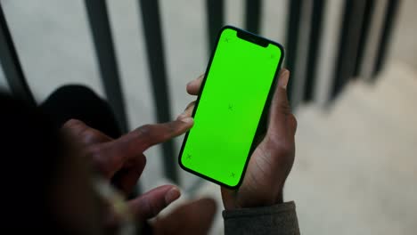 person holding a smartphone with a green screen