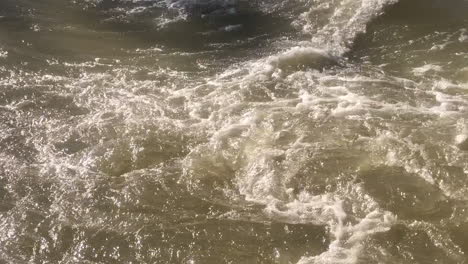 Aerial top down close up view of turbulent and powerful river water flow
