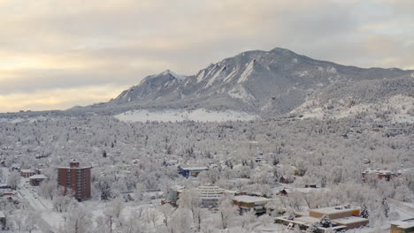 Tiro-Alto-De-Drones-Moviéndose-A-La-Derecha-De-Boulder-Colorado-Y-Montañas-Rocosas-Flatiron-Después-De-Una-Gran-Tormenta-De-Nieve-Invernal-Cubre-árboles,-Casas,-Calles-Y-Vecindarios-En-Nieve-Blanca-Fresca-Para-Las-Vacaciones