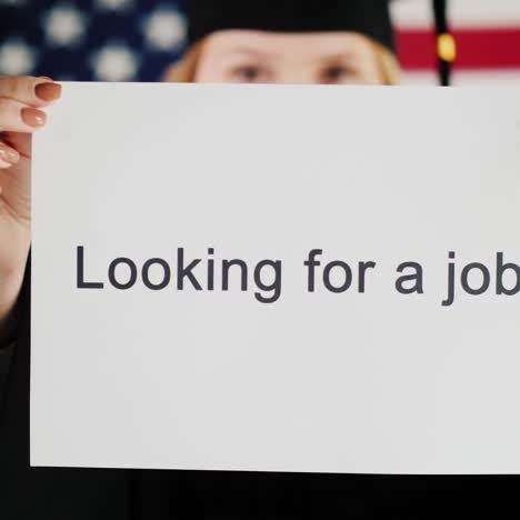 a graduate in a mantle and cap is holding a poster about job employment