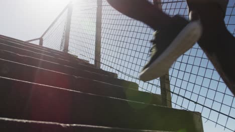 focused african american man running up the stairs, exercising outdoors on sunny day