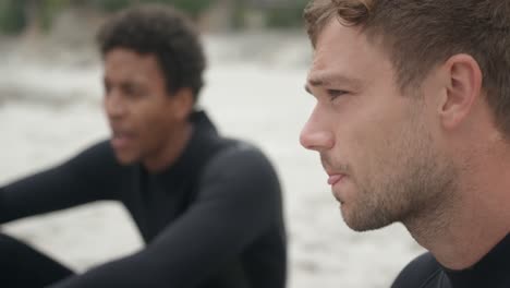 vista lateral de dos surfistas masculinos relajándose en la playa 4k