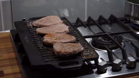 spraying oil on steaks on grill. handheld