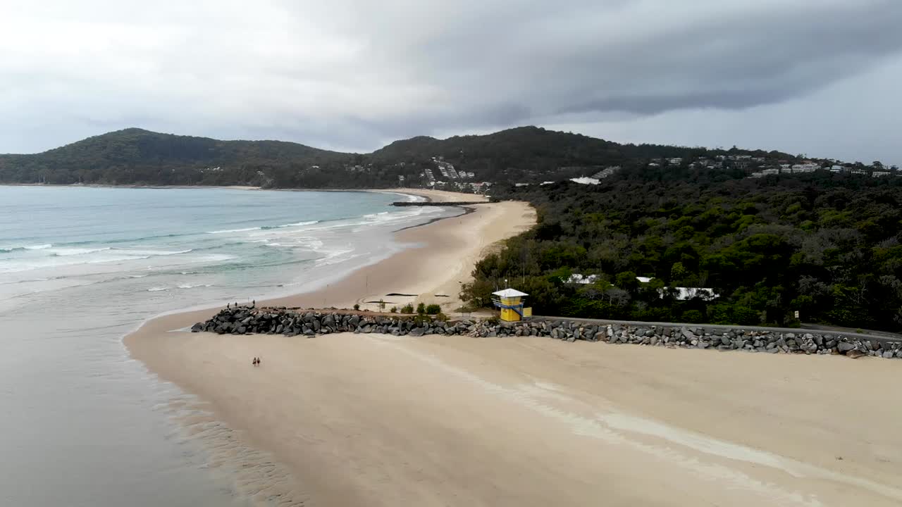 olas en las arenas blancas de australia, amanecer con el club de surf al fondo