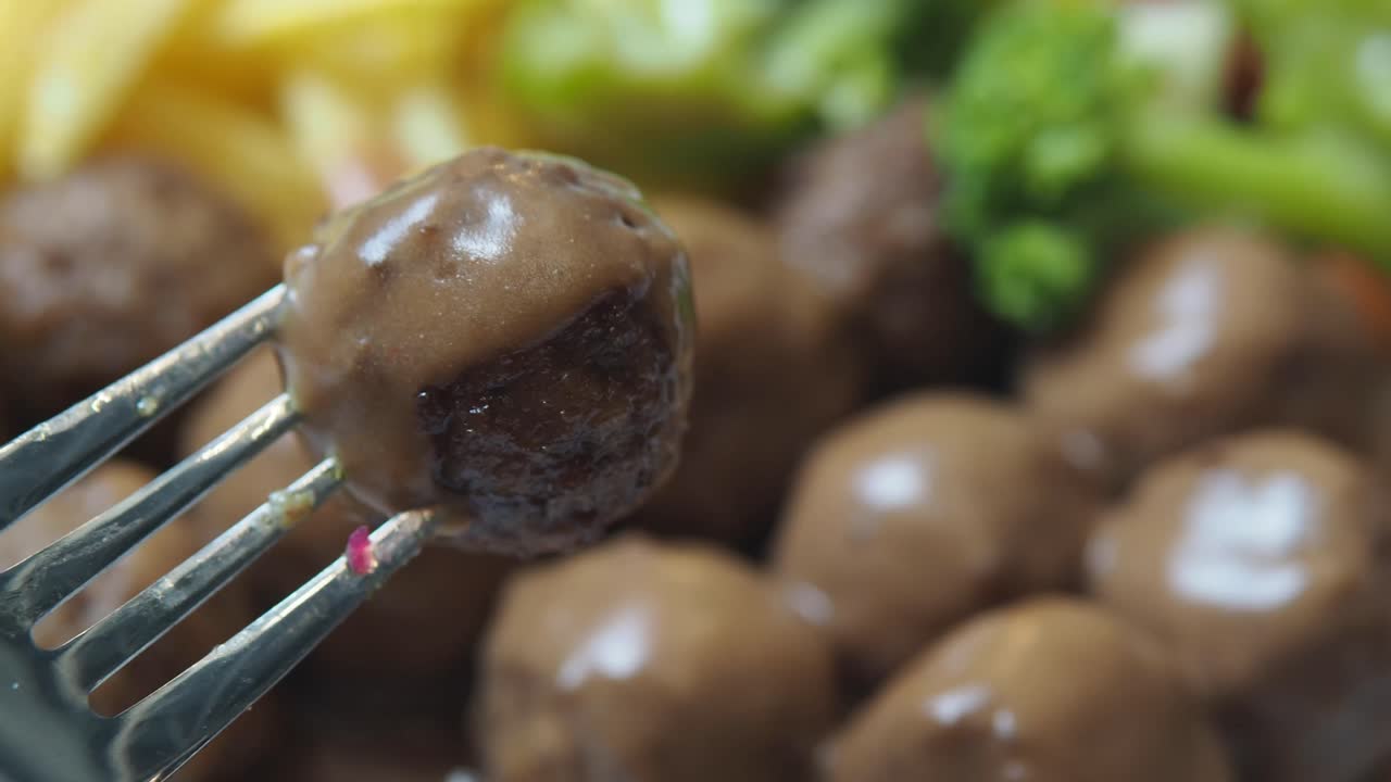 Close-up of a meatball on a fork with gravy