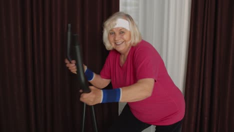 Senior-woman-in-sportswear-using-orbitrek-in-room-at-home-doing-sport-training-cardio-exercises