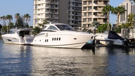 a yacht navigates past buildings in a sunny cityscape