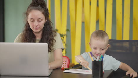 mother working from home while child draws