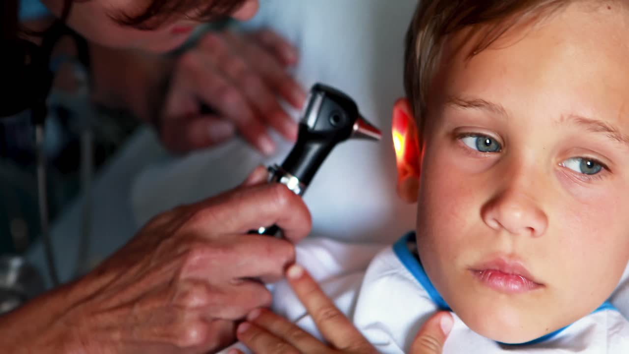 Female doctor examining patient ear with otoscope