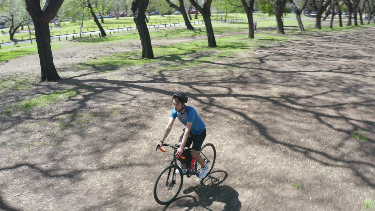 Cyclist Riding Bike along Dirt Road in the Park