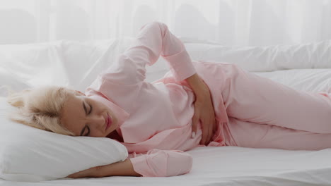 mujer que experimenta dolor abdominal en la cama