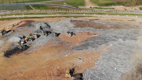 aerial view of landfill, trucks and equipment at dump, vultures and scavengers flying at waste and dump