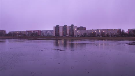 hermosa vista de lapso de tiempo del horizonte de la ciudad de liepaja, lago liepaja en primer plano, edificios de apartamentos distantes, noche nublada con nubes de lluvia en rápido movimiento, gotas de lluvia en la lente, amplia toma panorámica