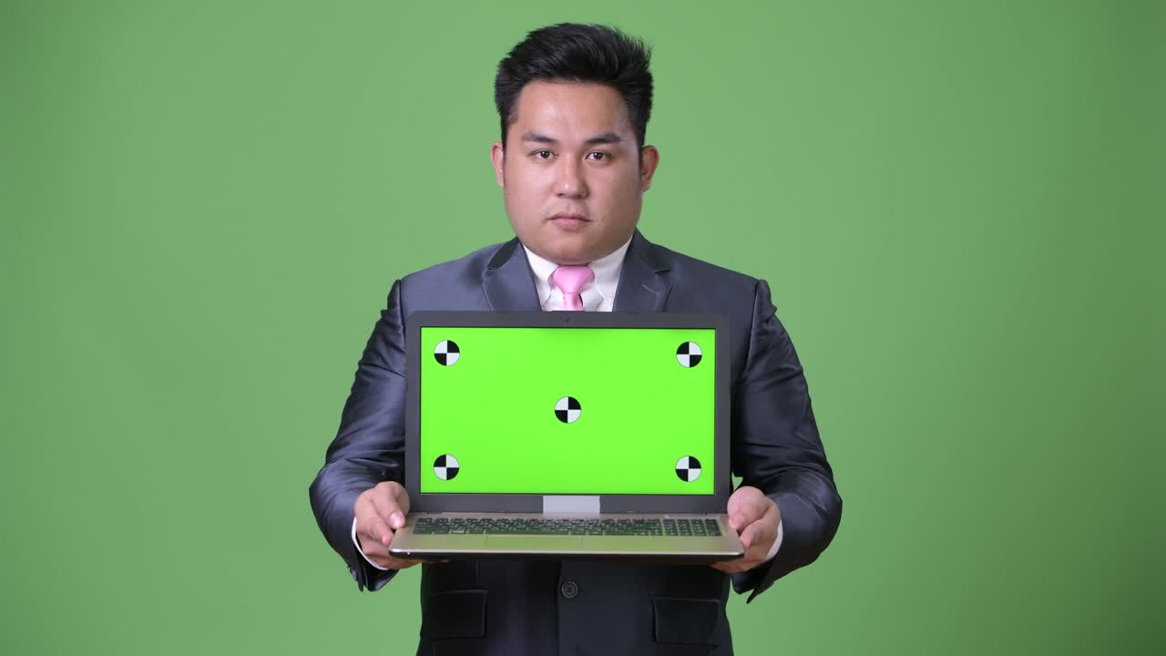 초록색 배경에 젊은 잘생긴 과체중 아시아 사업가