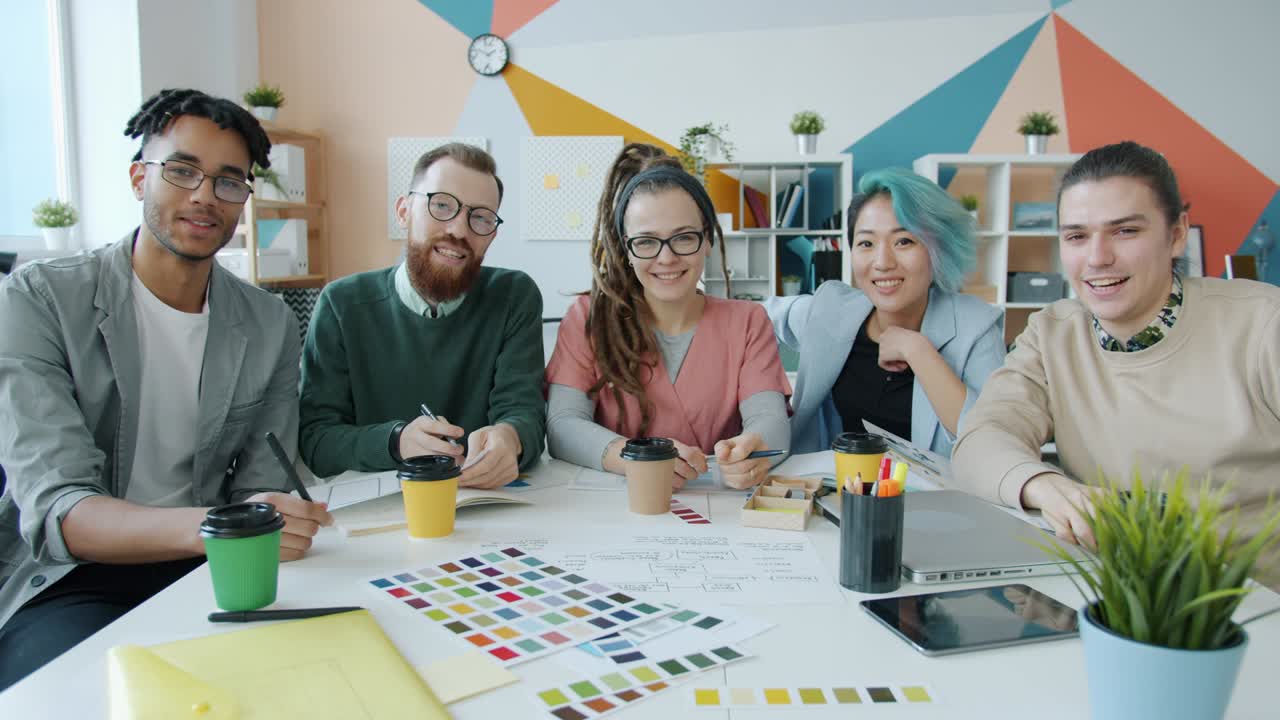 grupo multirracial de jóvenes creativos agitando la mano y hablando durante una videoconferencia en línea en la oficina