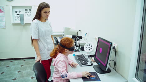 little girl at ophthalmologist. beautiful female doctor checking her visual acuity