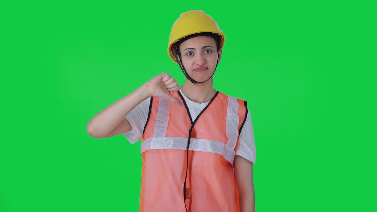 초록색 화면 아래 엄지 손가락을 보여주는 화가 난 인도 여성 건설 노동자