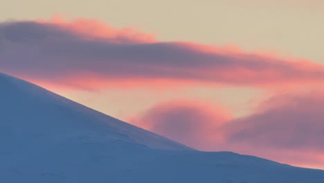 sunset light and rolling clouds above peaks of a snow covered mountains of northern norway in winter, timelapse, beautiful nature footage, long duration