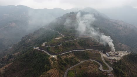 an aerial view of the bardibas or bp highway with smoke billowing from a nearby pavement production plant in nepal