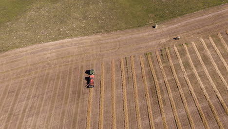 Toma-De-Arriba-Hacia-Abajo-De-Una-Maquinaria-Agrícola-Empacando-Una-Fila-De-Heno-En-El-Campo-En-Saskatchewan,-Canadá---Antena