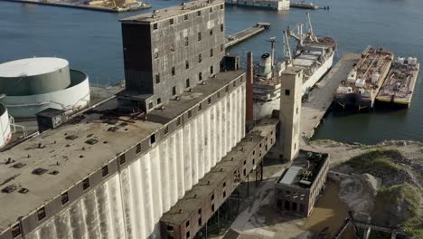 aerial flight next to massive abandoned grain terminal and industrial ships in brooklyn new york city