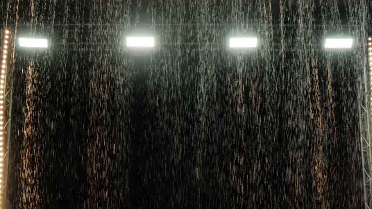 The effect of rain in the aqua studio against the background of spotlights. Water texture. Slow motion