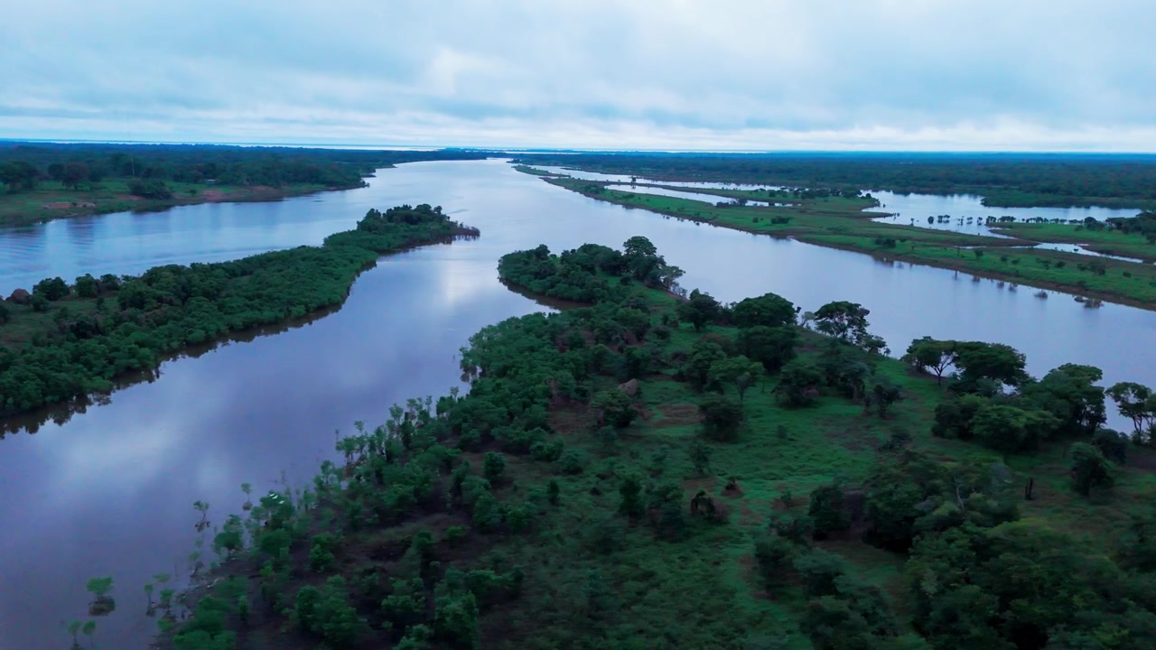River waters flowing through tropical landscapes in the Brazilian Amazon Basin during the evening, showcasing waterways, lush vegetation and cloud reflections, aerial view