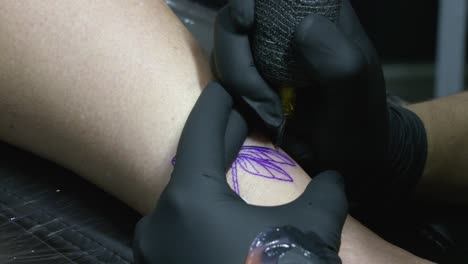 the tattoo artist neatly follows the lines of the drawing with the needle of his tattoo machine