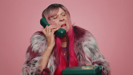 Crazy-hotline-agent-old-woman-talking-on-wired-vintage-telephone-of-80s-fooling-making-silly-faces