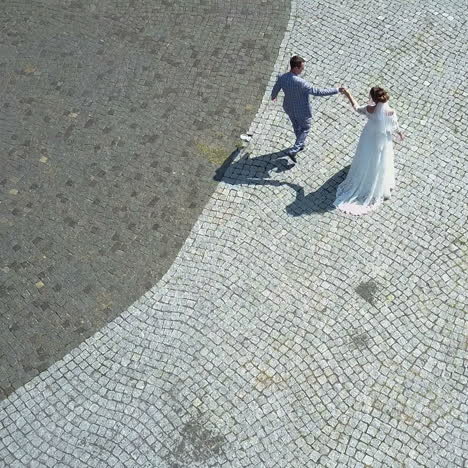 aerial view. wedding couple walks on old european city street. just married square video