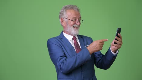 handsome senior bearded businessman against green background
