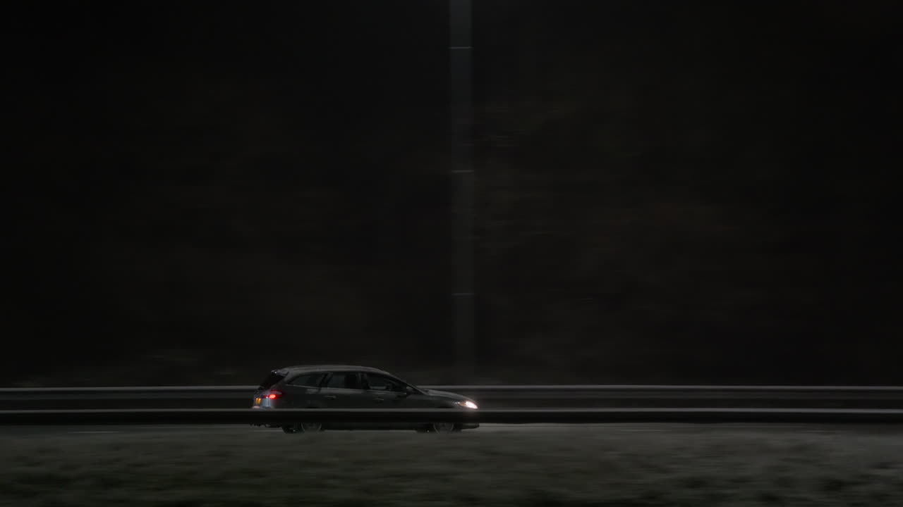 Vista lateral de autos circulando en una carretera oscura de noche