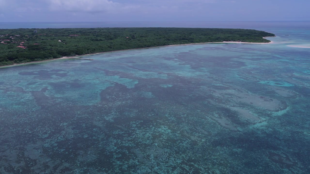 Filmato aereo orizzontale che si sposta a destra sopra la barriera corallina e le acque turchesi poco profonde vicino al molo di Nishi e alla spiaggia di Kondoi, Isola di Taketomi, Okinawa, Giappone.