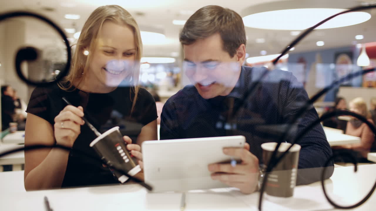 휴식 시간 에 카페 에 있는 동료 들 이 커피 를 마시고 패드 를 사용 하면서 대화 하고 있다