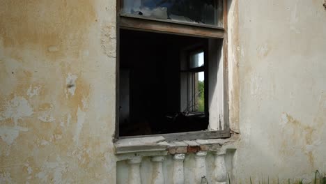 long smooth slowmotion shot of white abandoned house with broken window