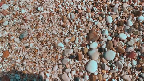 beach with colored pebbles on a sunny day with sea wave