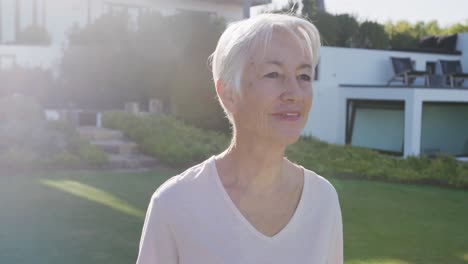 portrait of happy senior caucasian woman in garden on sunny day at retirement home