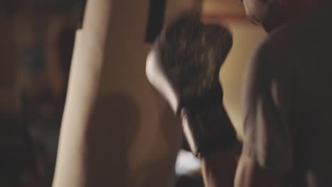back view of a man in gloves hitting the punching bag in the gym